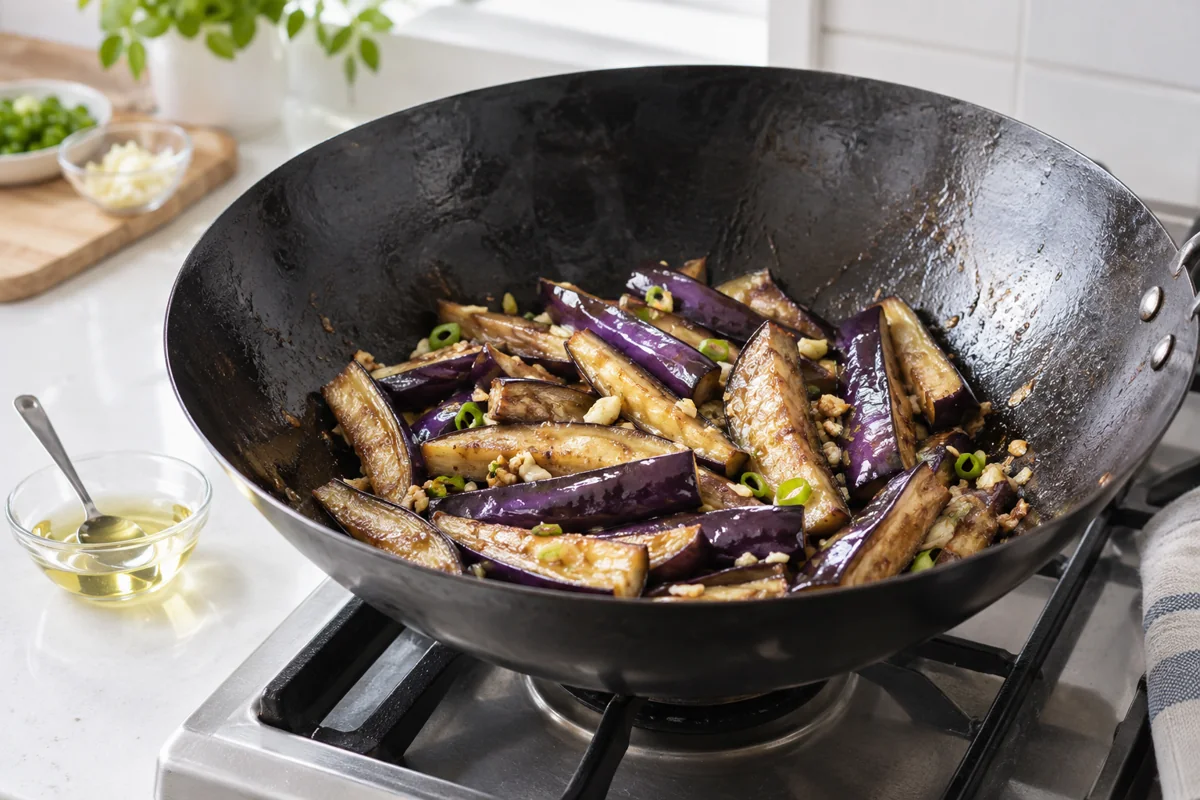 Long purple eggplant wedges with a modest oil measure beside the wok